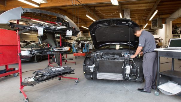 employee disassembling car front bumper and inspecting